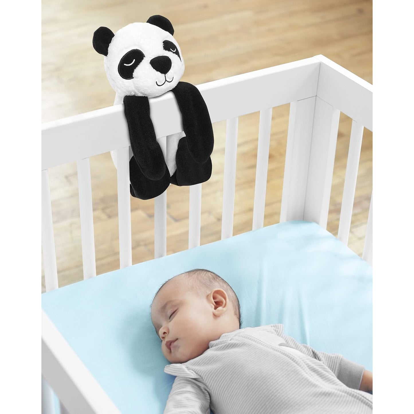 Peluche panda blanco y negro en cuna con bebé dormido, decoración infantil