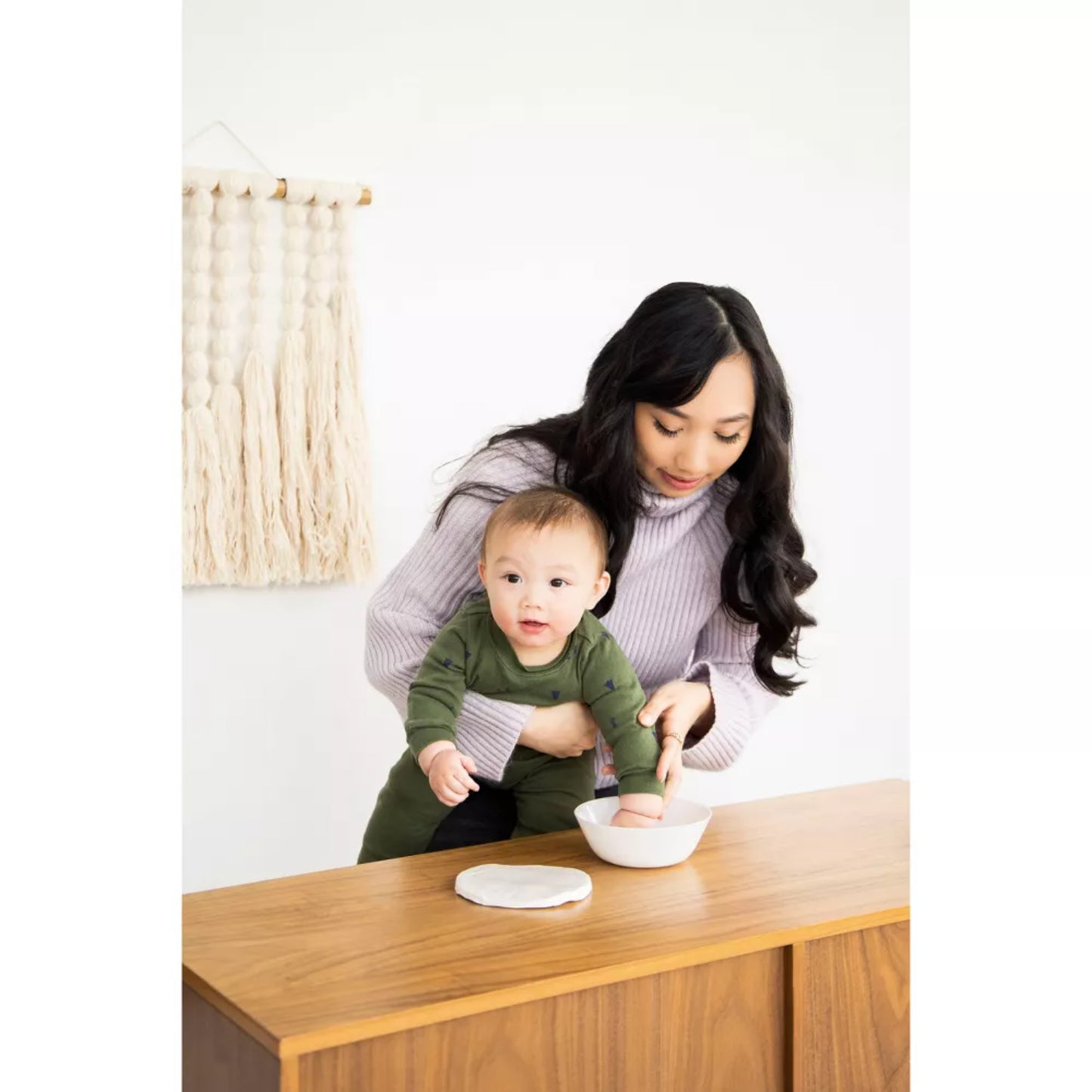 madre con bebé verde, preparando comida en mesa de madera