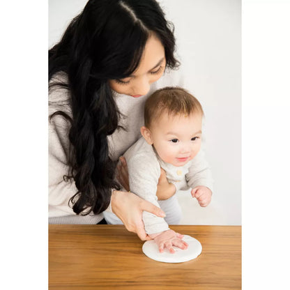 Huella de mano baby, madre ayudando al bebé en mesa de madera