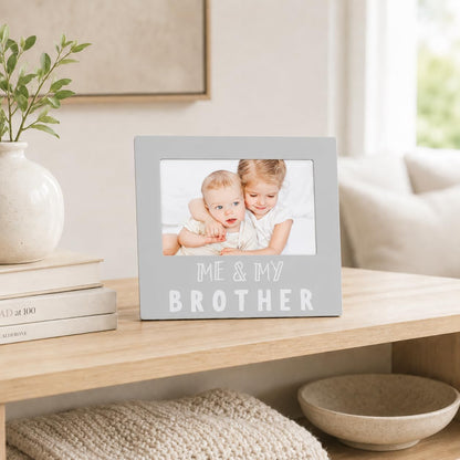 Marco de fotos gris con frase 'Me y mi hermanos' en mesa decorativa