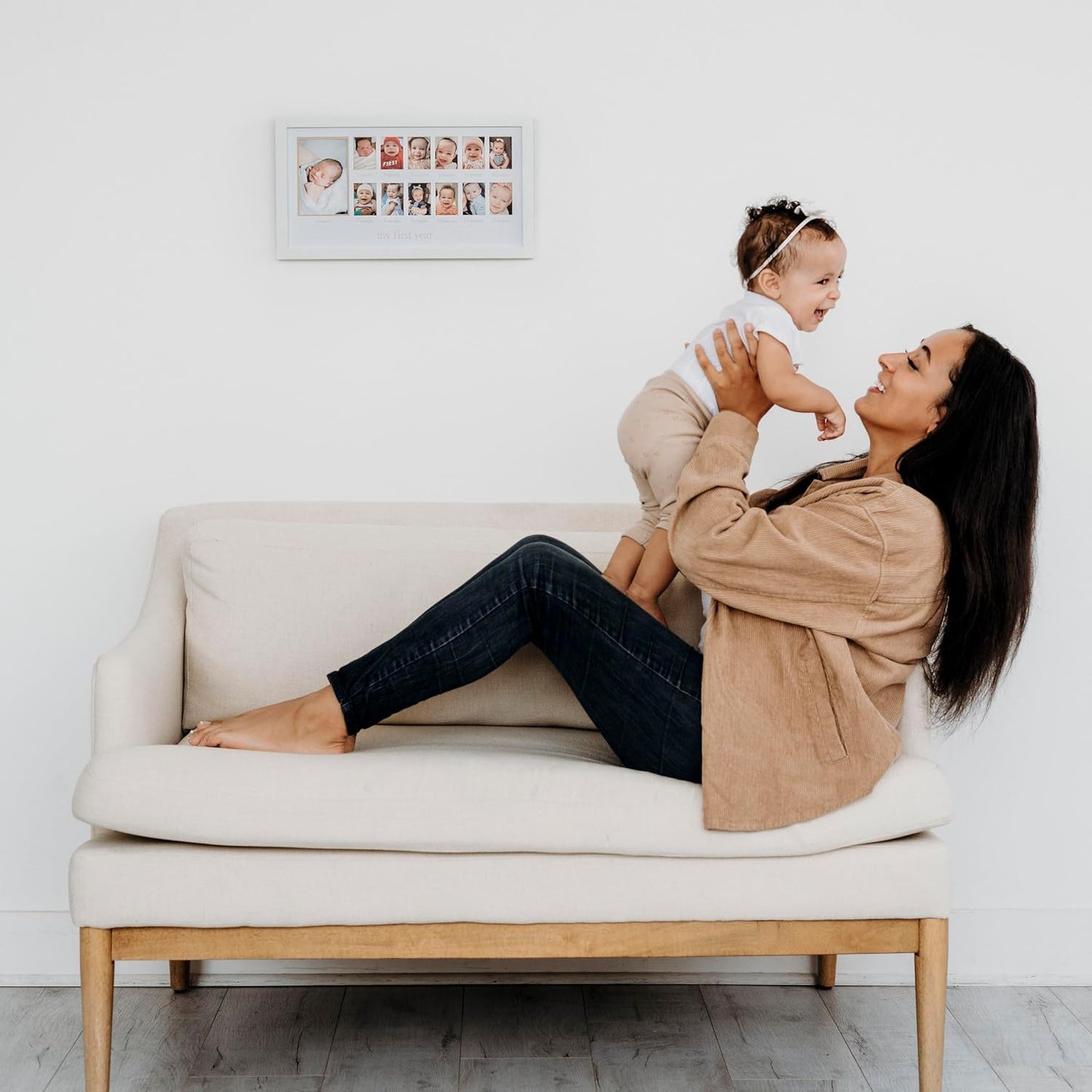 mujer sonriente con bebé en sofá blanco, ambiente familiar