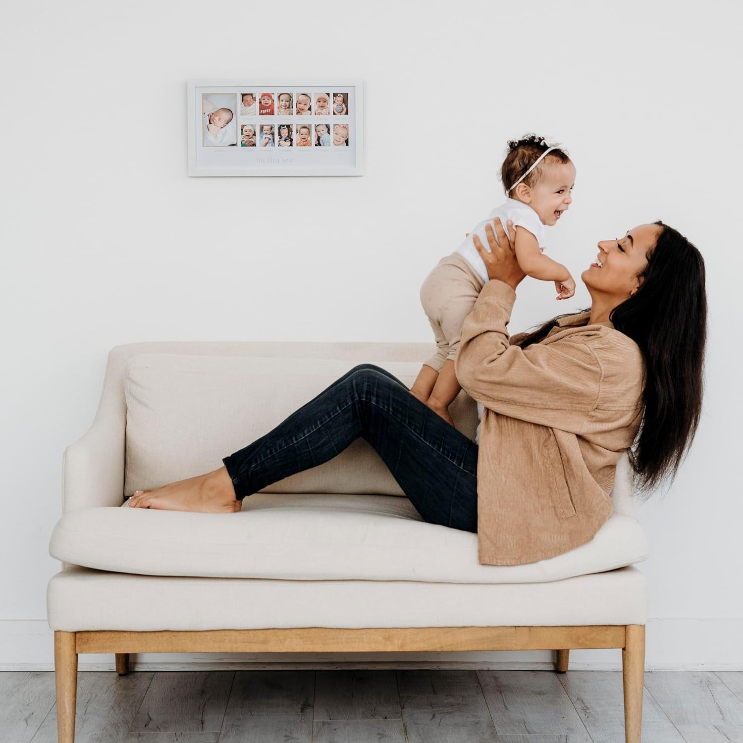 mujer sonriente con bebé en sofá blanco, ambiente familiar