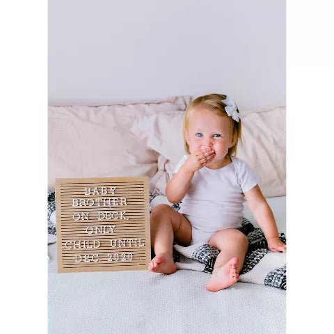 Pizarra de madera con texto y niño pequeño sentado en cama suave
