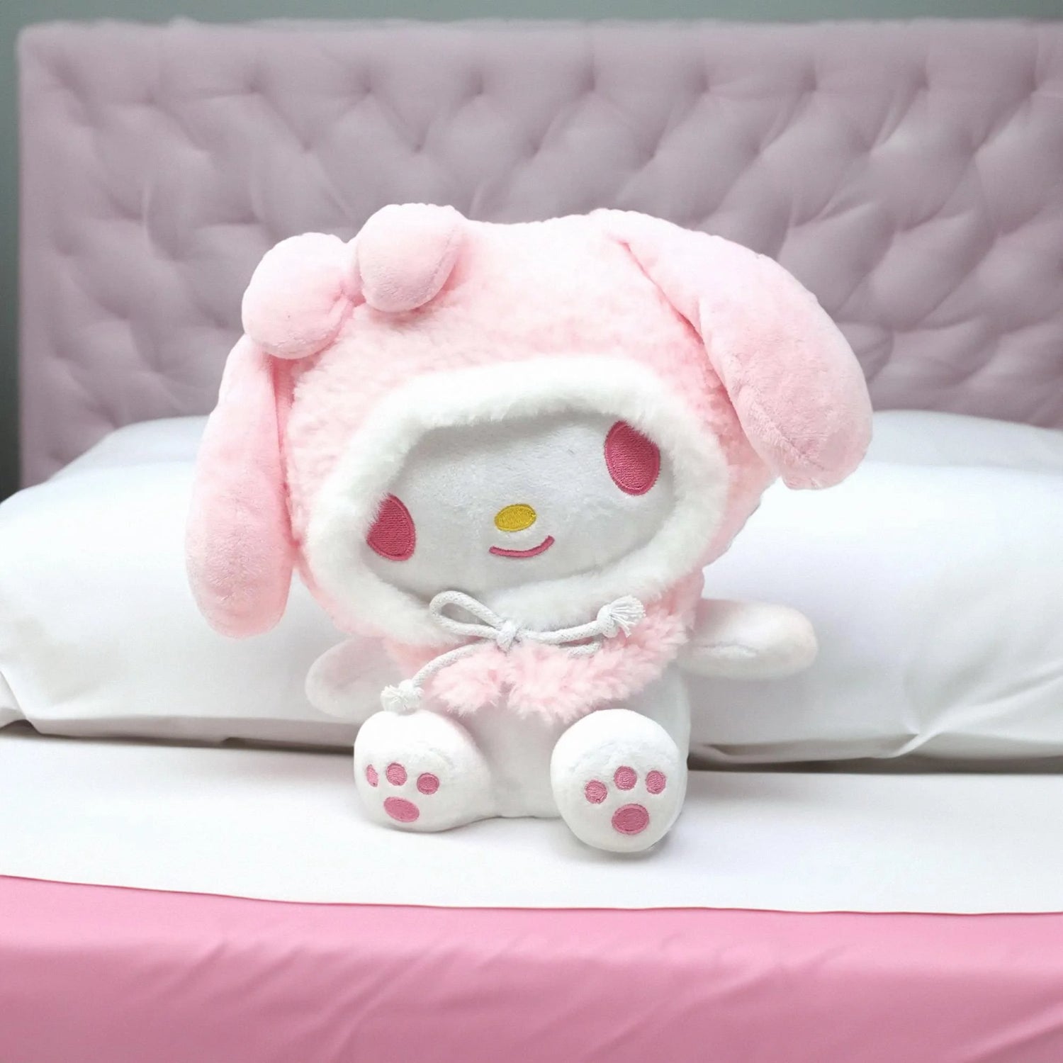 Peluche Sanrio de My Melody, color rosa con orejas largas, sobre cama blanca.