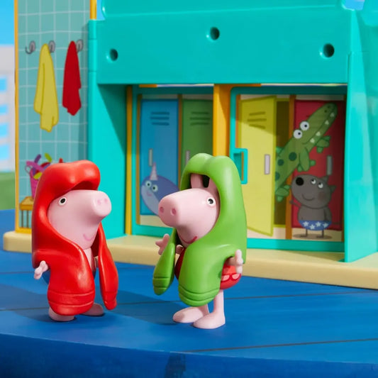 Figuras de Peppa Pig en toallas, parque acuático colorido de fondo