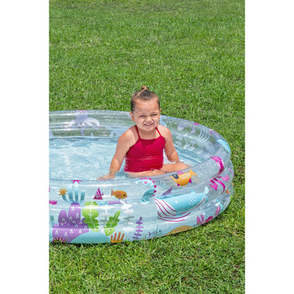 Piscina hinchable infantil transparente con dibujos coloridos y niña contenta dentro