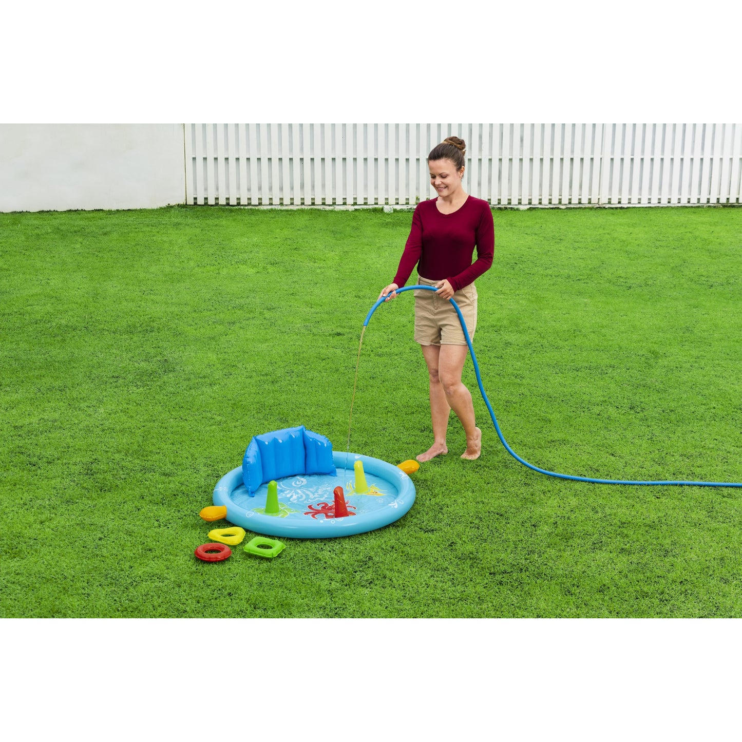 piscina infantil con accesorios azul, vista lateral en el jardín