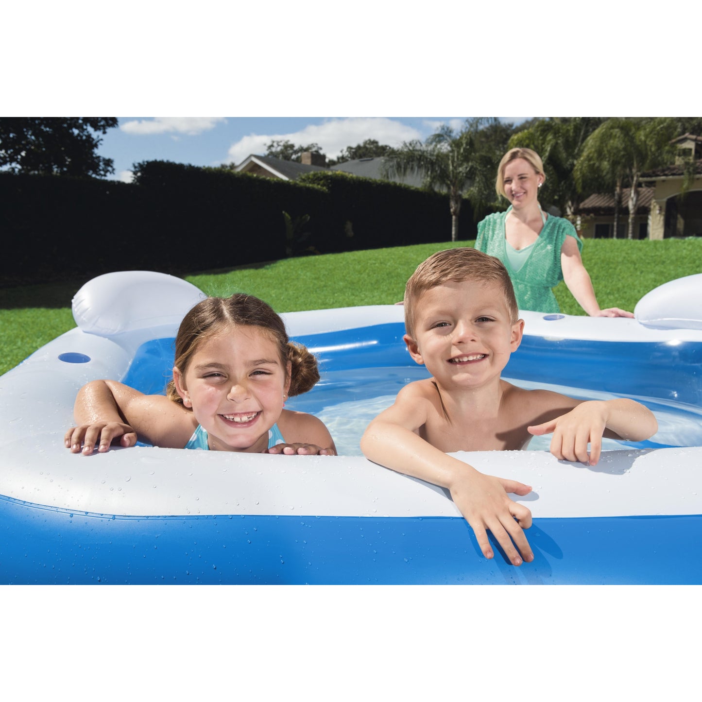 Piscina inflable familiar azul en jardín con niños jugando y una madre supervisando