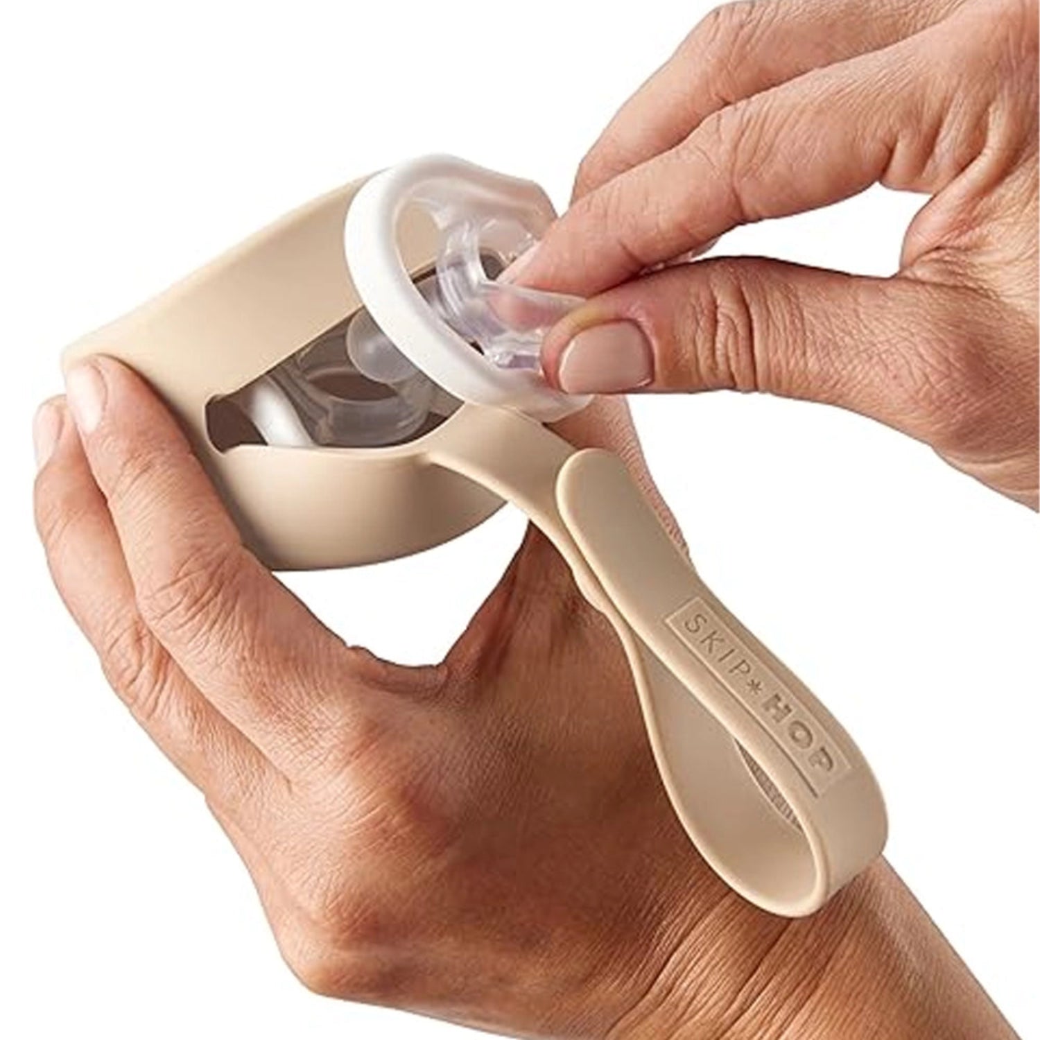 Portachup SKIP*HOP beige en mano, funcional y práctico para guardar chupetes