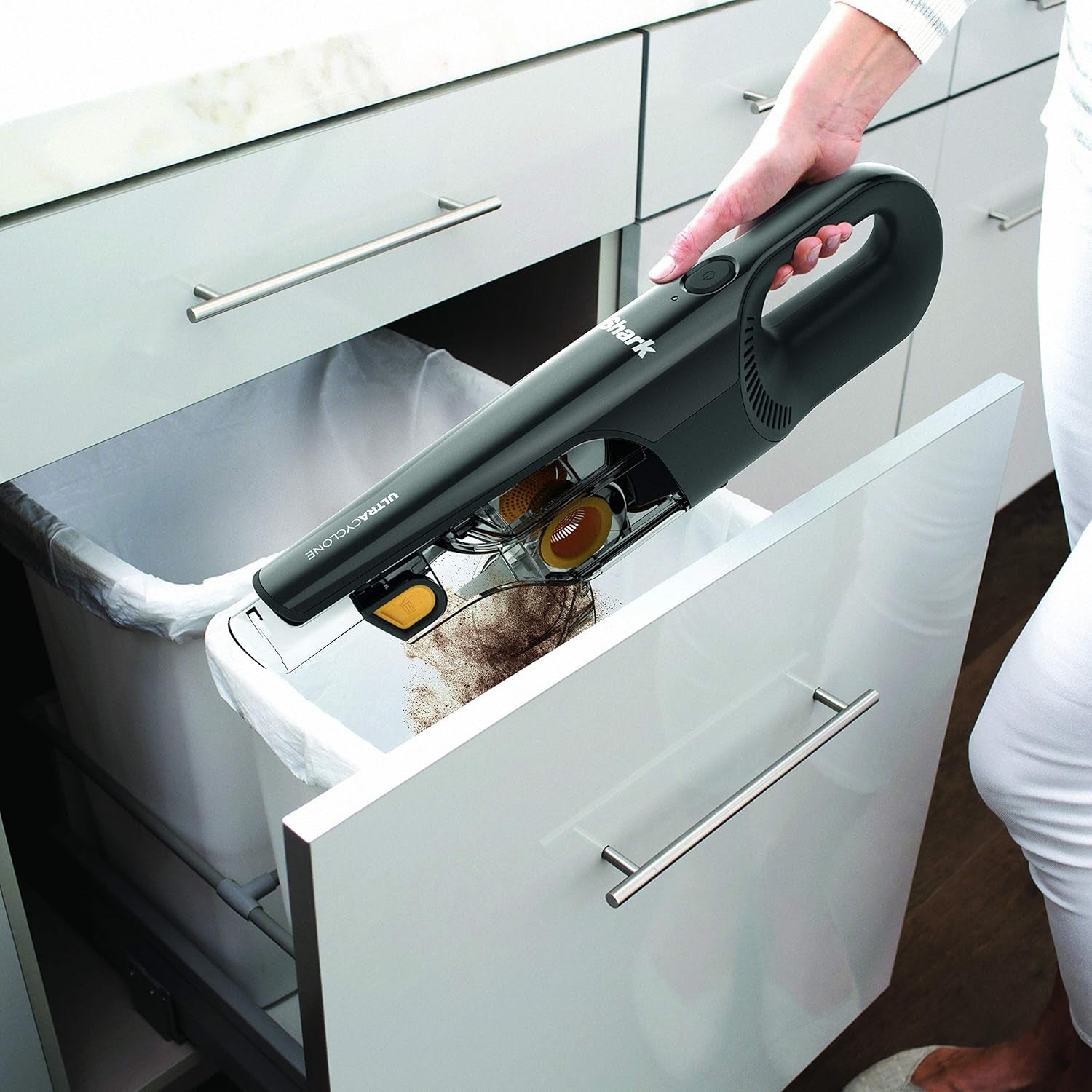 Aspiradora sin cable SHARK negra en uso, limpiando un cajón de cocina