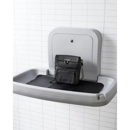 Cambiador gris montado en la pared con bolsa negra, ideal para baños infantiles