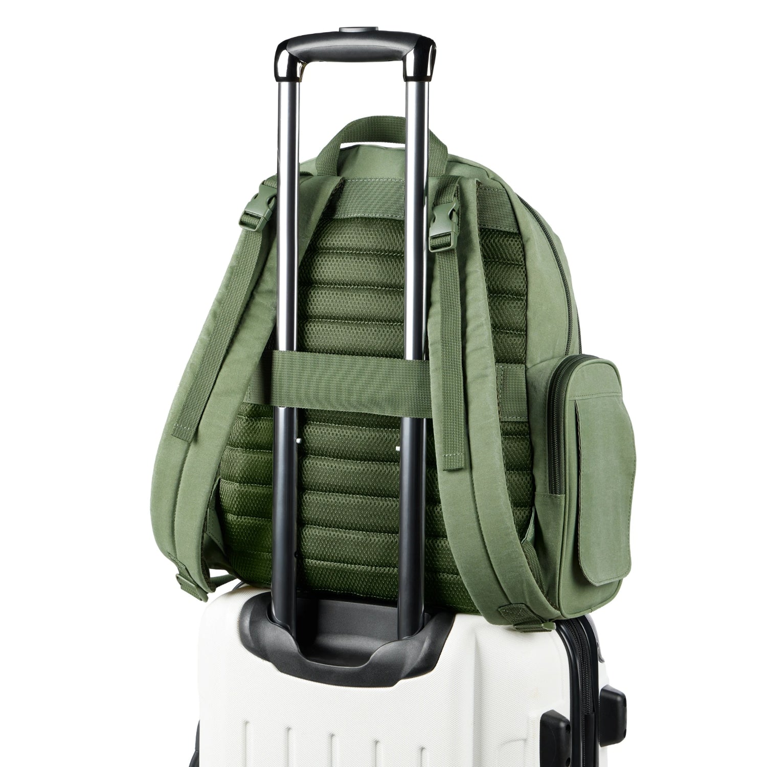 Pañalera verde con asas y correas, vista trasera sobre maleta