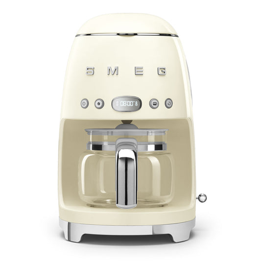 Cafetera SMEG color crema, vista frontal con jarra de vidrio.