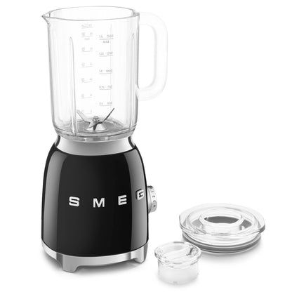 Licuadora negra SMEG vista frontal, cocina con accesorios separados