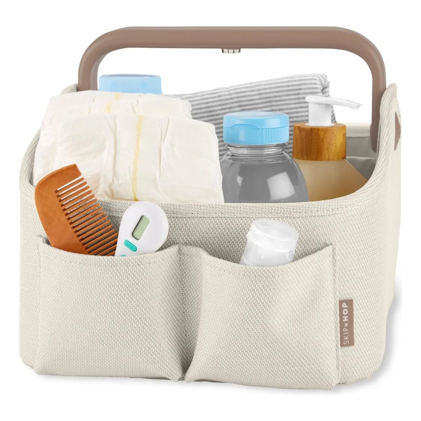 Organizador de pañales SKIP*HOP beige con asa, vista frontal y productos esenciales