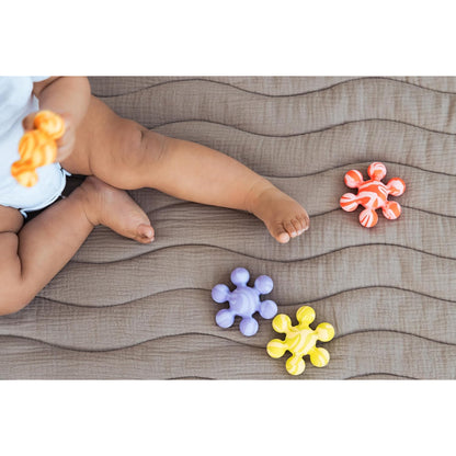 Juguetes de goma coloridos para bebés, vista desde arriba con un niño y un fondo texturizado