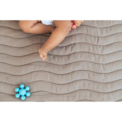 Manta para bebés en color beige con textura ondulada y juguete azul
